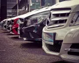 Rząd lśniących samochodów, w tym czerwony i biały Mercedes, gotowych do sprzedaży. Idealne miejsce na ubezpieczenie komisowe.