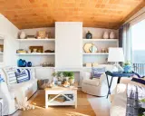 Salón con vistas al mar, decoración náutica y techo de tejas. Un espacio que evoca la sensación de estar en la playa en casa.