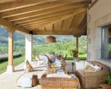 Ideas para como decorar porche de entrada: muebles de mimbre, mesa de comedor, un perro y vistas espectaculares.
