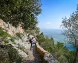 Mann mit Wanderstock und Rucksack genießt die Aussicht auf Mallorca. Ein toller Tag zum Wandern auf Mallorca!