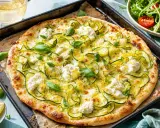 Délicieuse pizza courgette, ricotta et basilic, garnie de zeste de citron, sur une plaque de cuisson.