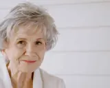 Ritratto di Alice Munro, con capelli grigi spettinati e un sorriso gentile.