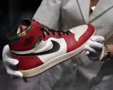 Ein ikonischer Air Jordan 1 Sneaker, der die Nike Air Jordan Geschichte verkörpert, wird von Händen in weißen Handschuhen präsentiert.