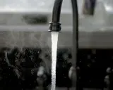 Un robinet ouvert, l'eau coule. Une image symbolisant l'ouverture du compteur d'eau pour un locataire.