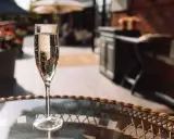 Ein Glas Sekt auf einem Tisch im Freien. Auch wenn Sekt kein Verfallsdatum hat, sollte er frisch genossen werden.