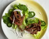 Crujiente oreja de cerdo frita servida sobre lechuga con cebolla morada, cilantro y jalapeño.