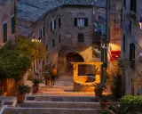 Un vicolo suggestivo a Montefeltro, cosa vedere: un pozzo antico, scalinate in pietra e luci soffuse creano un'atmosfera magica.