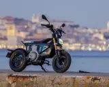 Une trottinette électrique BMW futuriste, aux lignes audacieuses, se dresse sur un quai, la ville illuminée en arrière-plan.