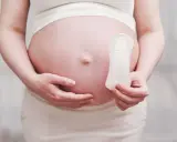 Ciężarna kobieta trzyma podpaskę, sugerując pytanie: czy w okres można zajść w ciążę?