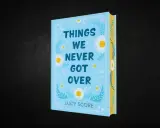 Okładka książki "Things We Never Got Over" Lucy Score. Jasnoniebieska okładka z motywem stokrotek i liści.