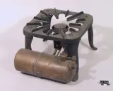 Gammalt fotogenkök i metall med en brännare och en bränsletank. Märkt "SVEA KOMFUR".