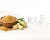Cukier trzcinowy w misce i kawałki trzciny cukrowej. Czy cukrzyk może używać cukier trzcinowy? Ikony posiłku, serca i liścia sugerują zdrową dietę.