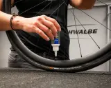Eine Hand gibt Dichtmilch in den Fahrradschlauch eines Schwalbe Reifens.
