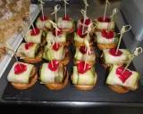 Variedad de tipos de pinchos con calabacín enrollado, pétalos rojos y palillos de bambú.