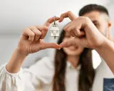 Un couple non marié célèbre son achat maison. Les mains forment un cœur autour de la clé, symbole de leur nouveau foyer, un nouveau départ après un décès.