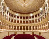 Interni sfarzosi del teatro Amintore Galli, con poltrone rosse e decorazioni dorate. Scopri i prossimi eventi!