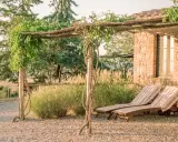 Due lettini prendisole sotto un pergolato fiorito, un'oasi di pace per il tuo itinerario Val d'Orcia.