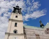 Wieża kościoła w Gidlach pod błękitnym niebem z chmurami. Widać fragment dachu w rusztowaniach.