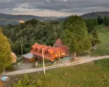 Malowniczy dom z czerwonym dachem w otoczeniu zielonych wzgórz. Idealne miejsce na agroturystykę w Pieninach, gdzie można odpocząć od zgiełku.