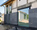 Panneaux de polystyrène gris fixés sur le mur d'une maison en construction, étape de l'isolation par l'extérieur.