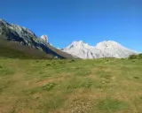 Majestatyczne szczyty Picos de Europa, w tym charakterystyczny Torre de Cerredo, wznoszą się nad zieloną doliną.
