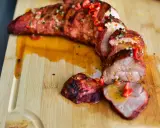 Saftige **Lende auf dem Grill**, in Scheiben geschnitten und mit roten Chilis und Kräutern garniert. Ein köstlicher Anblick!
