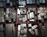 Metalowe czcionki do druku, czyli poligrafia co to. Litery i cyfry w przegródkach, gotowe do tworzenia tekstu.