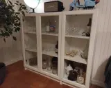 Ett DIY-projekt med ett vitt Billy vitrinskåp fyllt med glas, flaskor och dekorationer.