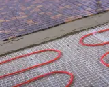 Układanie mozaiki na siatce z przewodami do ogrzewania podłogowego. Przewody ułożone co 10-15 cm zapewnią komfort cieplny.