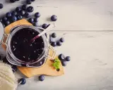 Frische Heidelbeeren und selbstgemachte Heidelbeermarmelade im Glas, bereit zum Genießen.