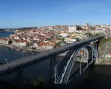 El icónico puente de Oporto cruza el río Duero, conectando la ciudad con sus coloridas casas y barcos turísticos.