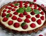 Tarta z mascarpone i białą czekoladą, ozdobiona malinami i miętą. Pyszny deser na każdą okazję.