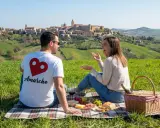 Coppia in un prato verde con vista su un borgo collinare. Perfetto per scoprire cosa fare a Pasquetta nelle Marche con un picnic.