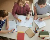 Trzech studentów pracuje nad pracą licencjacką, analizując metody badawcze.