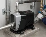 Pompa per acqua con pannello digitale. Un tecnico con guanti bianchi regola una valvola, forse per controllare il rumore pressione acqua.