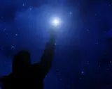 Sylwetka człowieka sięga ku jasnej gwieździe polarnej na tle nocnego, gwiaździstego nieba.