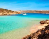 Traumhafter Malta Strand mit türkisfarbenem Wasser, einer einsamen Bucht und einem Segelboot. Perfekt für einen entspannten Urlaub.
