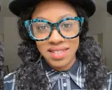 Frauen mit pigtails hair, auffälligen Brillen und kariertem Hemd lächeln in die Kamera.