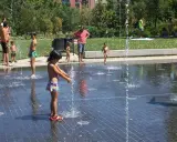 Niños y adultos disfrutan del agua en las fuentes del madrid rio parque.