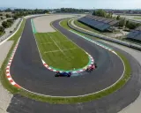 Dos coches de F1 compiten en una curva cerrada de los circuitos F1, uno azul derrapa y el otro rojo acelera.