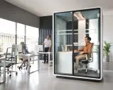 Aménagement open space ergonomique : un bureau moderne avec des postes de travail ouverts et une cabine insonorisée pour la concentration.