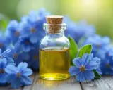 Flacon d'huile de bourrache aux multiples bienfaits, entouré de fleurs bleues délicates sur fond vert.