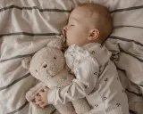 Kleines Kind schläft friedlich mit Teddybär. Die **Schlafregression 1 Jahr** ist eine Herausforderung, aber dieser süße Anblick tröstet.