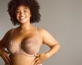 Donna sorridente con tette grandi perfette in reggiseno di pizzo color carne.
