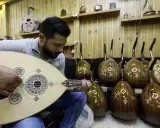 Un joueur de oud expérimenté accorde son instrument, entouré d'autres ouds prêts à être joués.