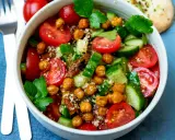 Frischer Couscous-Salat mit Kichererbsen, Tomaten und Gurken, garniert mit Petersilie.
