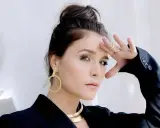 Jessie Ware, w czarnej marynarce, z dłonią na czole, jakby prosiła "say you love me". Złote kolczyki i naszyjnik dodają blasku.
