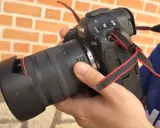 Mano sosteniendo una cámara Canon R1 con lente, lista para capturar momentos.