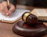 Młotek sędziowski i ręka pisząca na papierze. Zastanawiasz się, czy warto studiować prawo?
