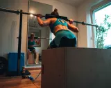 Frau beim Krafttraining für Triathlon, macht Kniebeugen mit Langhantel.
